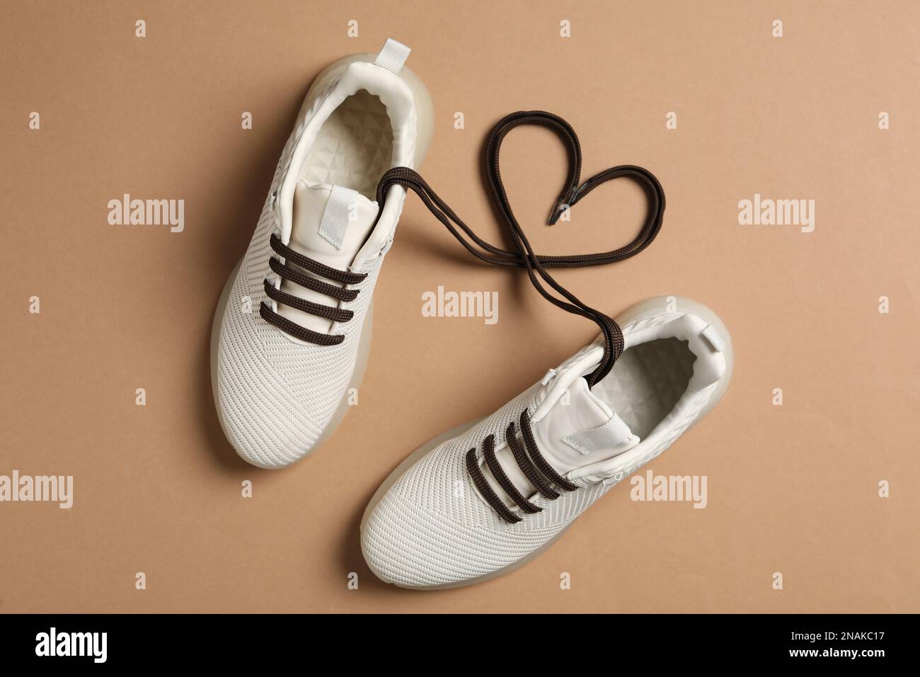 Stylish sneakers and shoe laces in shape of heart on brown background, flat  lay Stock Photo - Alamy